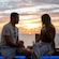 A couple enjoying beverages and the sunset on an outdoor bench at Infinity Bar on the Disney Adventure